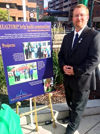 Matt Robertson standing next to his poster reading, "Realtors help build communities."