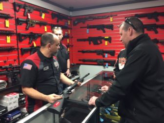 Employee at Not Just Guns discussing a firearm with customers.