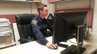 East Lansing Police Officer Jordan Woodruff sits at a computer and composes a tweet.