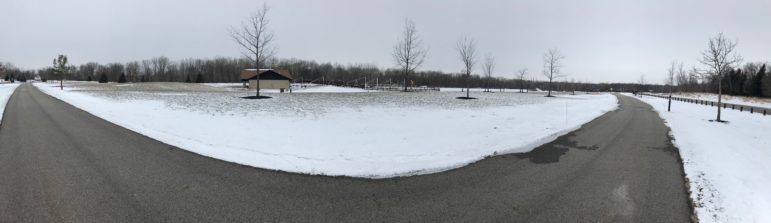A panorama of Hawk Island paved trails with snow in the background.