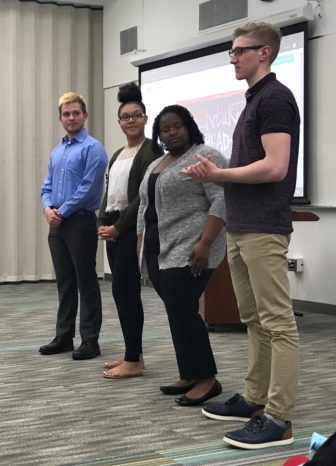 Four high school students at Wilson Talent Center stand in front of the ISD school board talking about their trip to D.C.