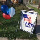 "Vote here" sign with red, white and blue balloons