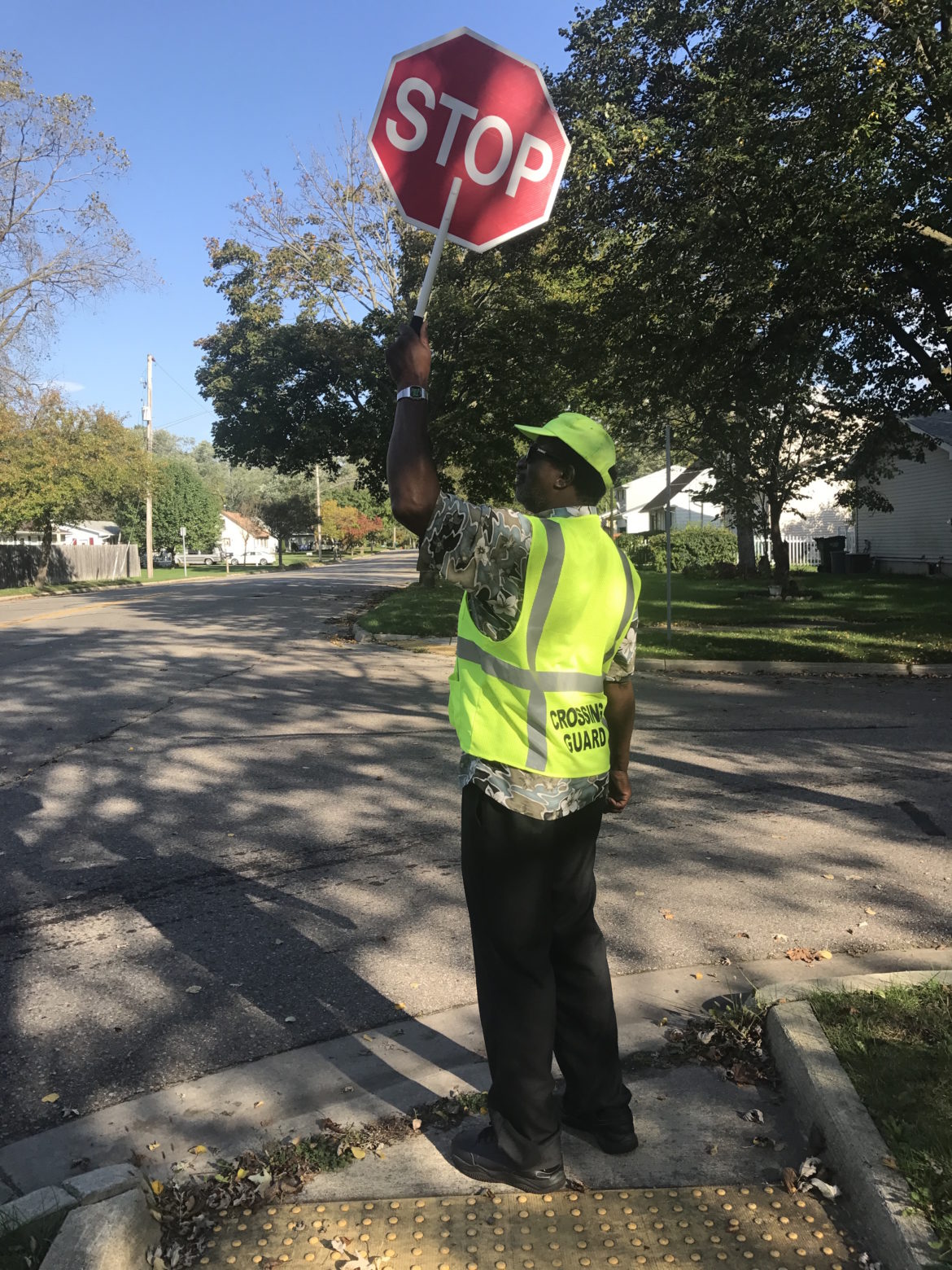 Alfred Anderson, a cross guard at Attwood Elementary School, stops traffic to let students cross the street.