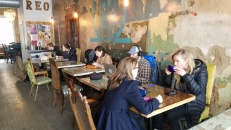 A row of small tables and chairs line one wall of Blue Owl Coffee's REO Town location.