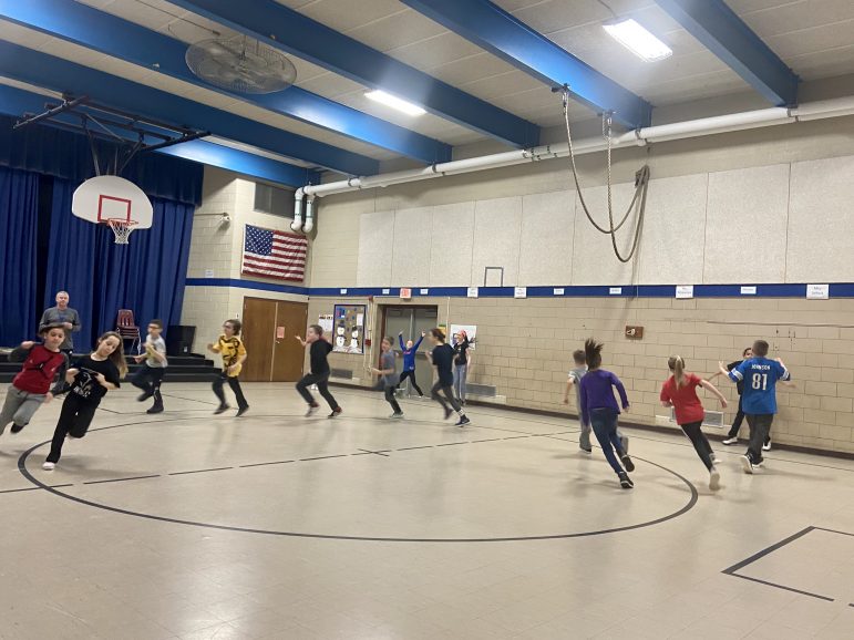 Children run in a circle in a gymnasium