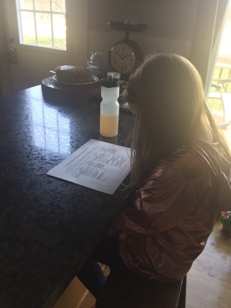 Third grade girl does homework at a kitchen table.