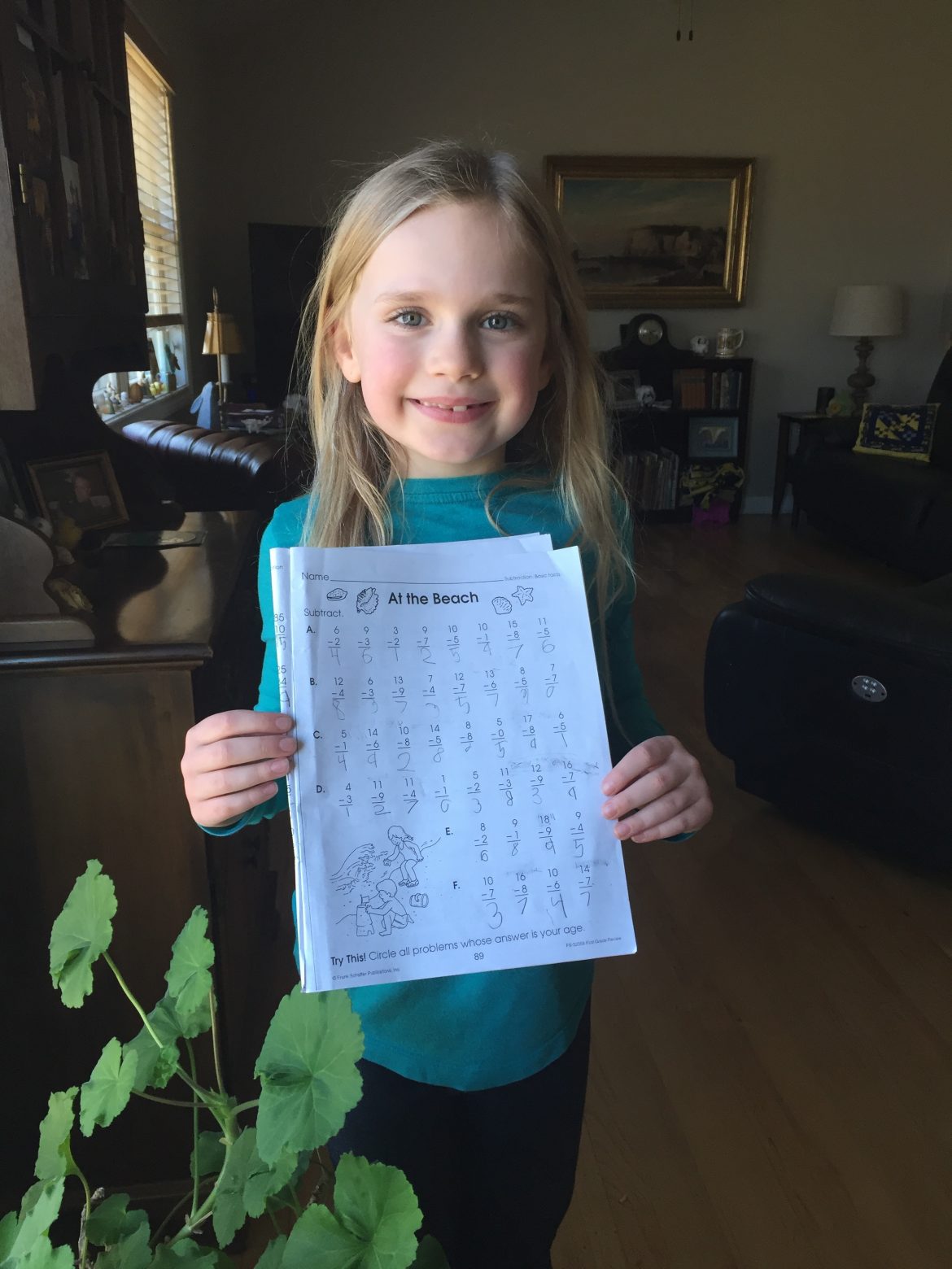 First grade girl holds learning packet.