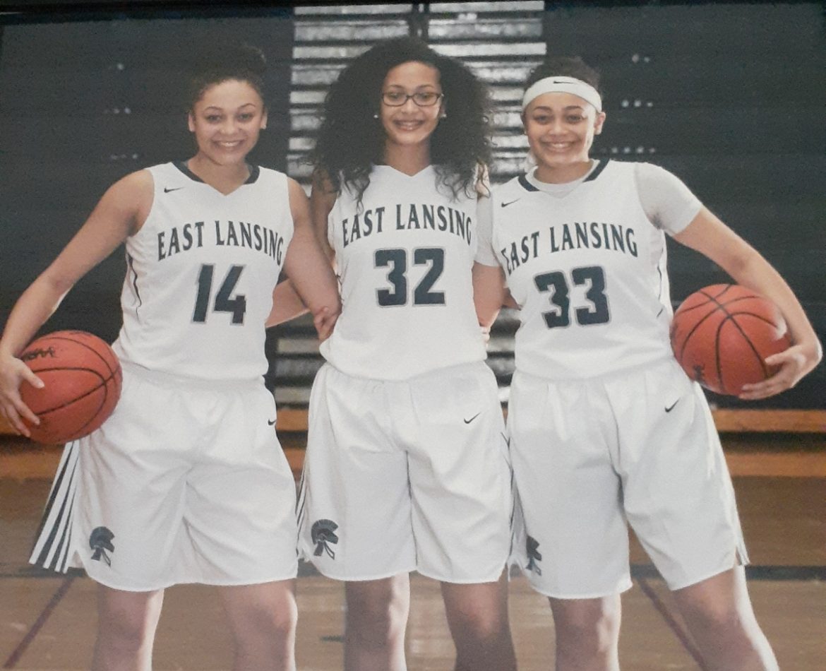 Three high school basketball players in uniform.