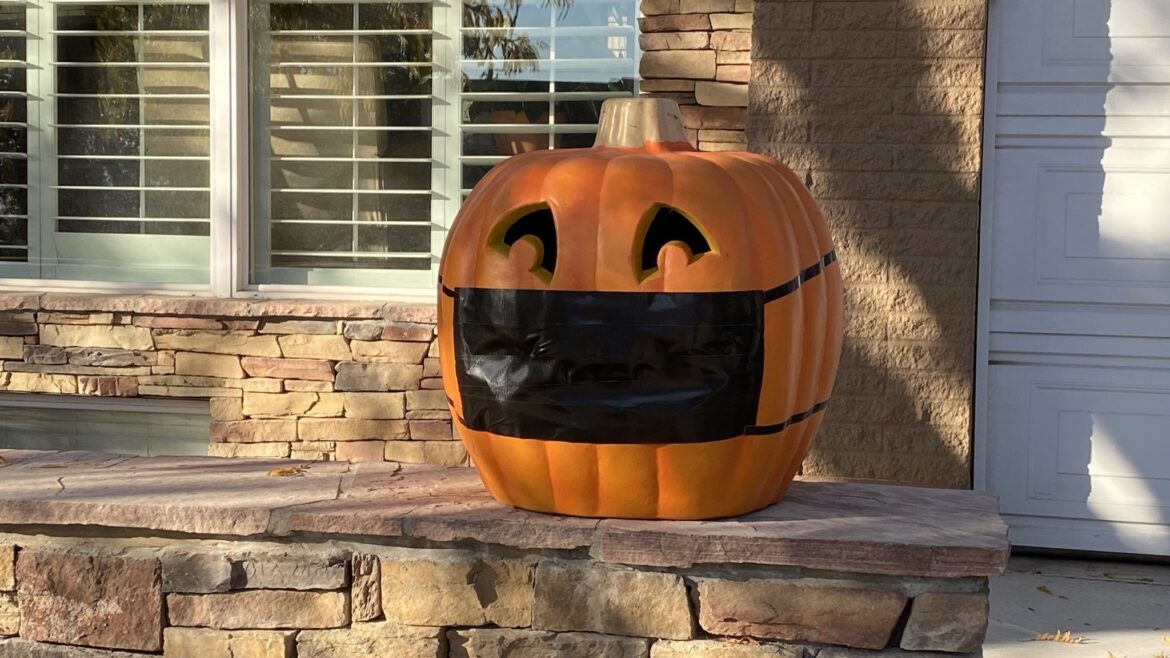 Pumpkin on a porch wearing a COVID-19 mask
