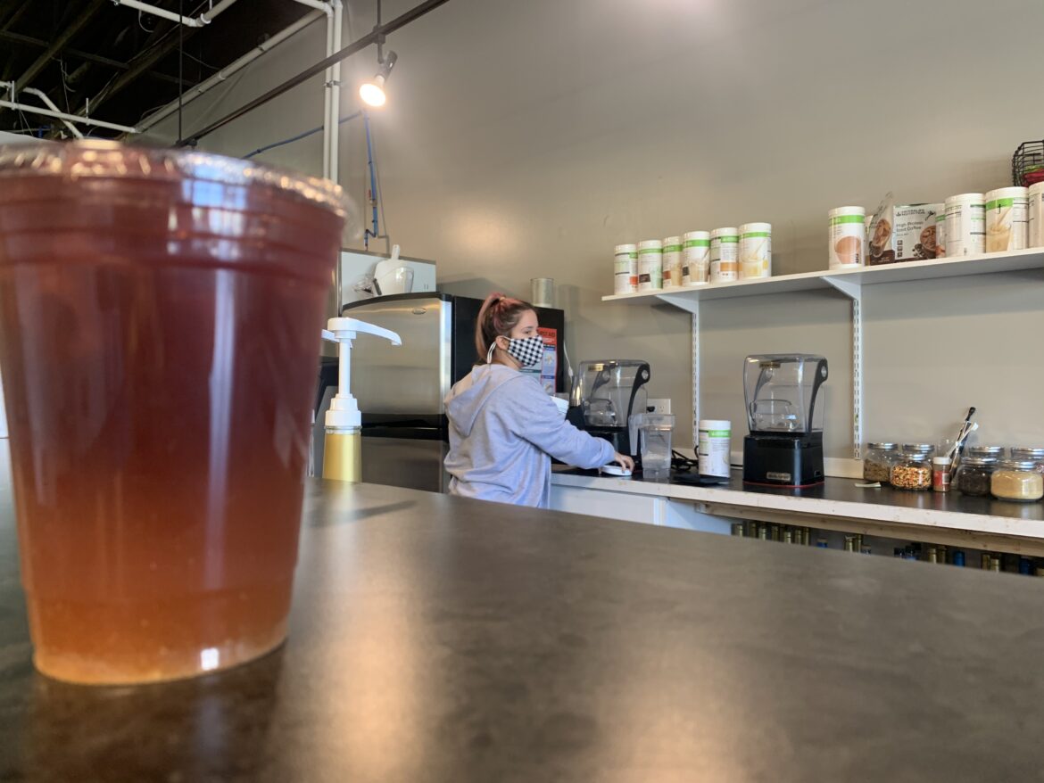 An employee works beyond the counter preparing a beverage at Central Lansing Nutrition.