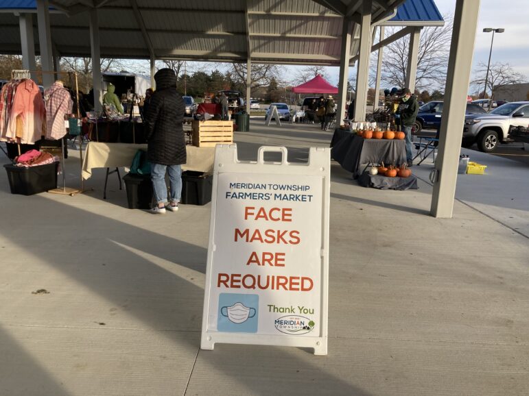 A sign at the Meridian Farmers Market in Ingham County reminds shoppers to mask up.