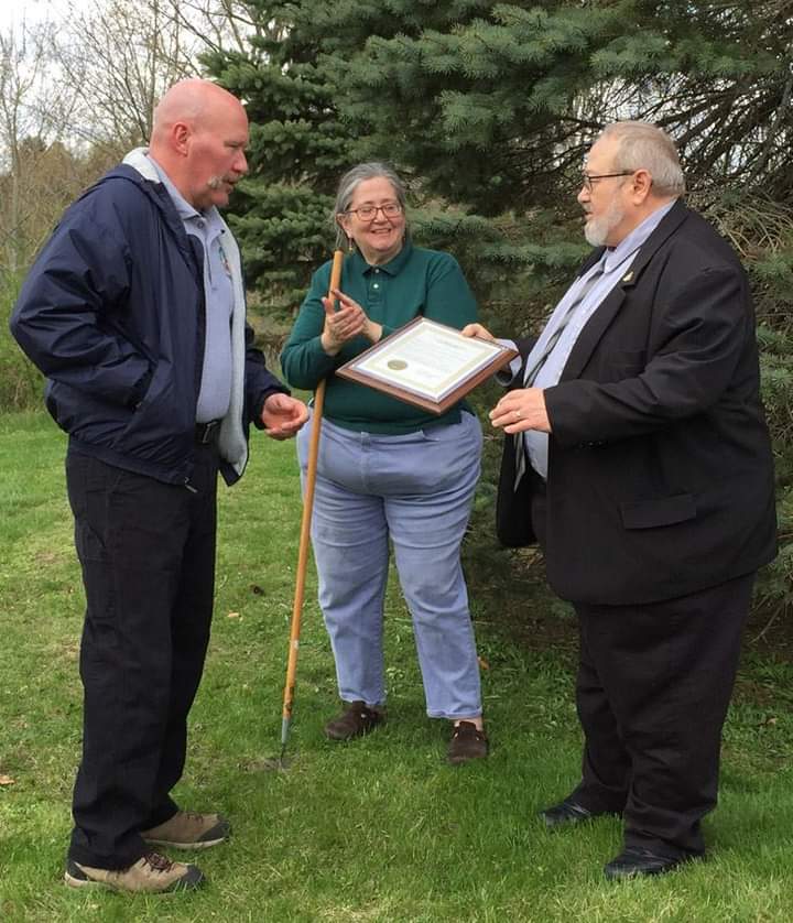 Three people outdoors with proclamation
