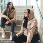 Yasmeen Kadouh, left, and Rima Imad Fadlallah sit in a stairwell modeling apparel for their podcast "Dearborn Girl."