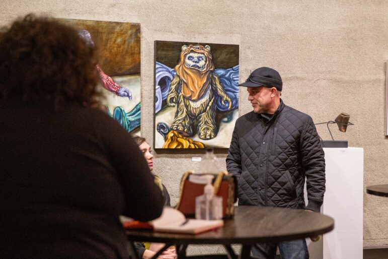 Brandon Navin, executive director for the Artist’s Umbrella, talks with attendees of the “Women’s Writes” open-mic event hosted at the MICA Gallery in Old Town Lansing.
