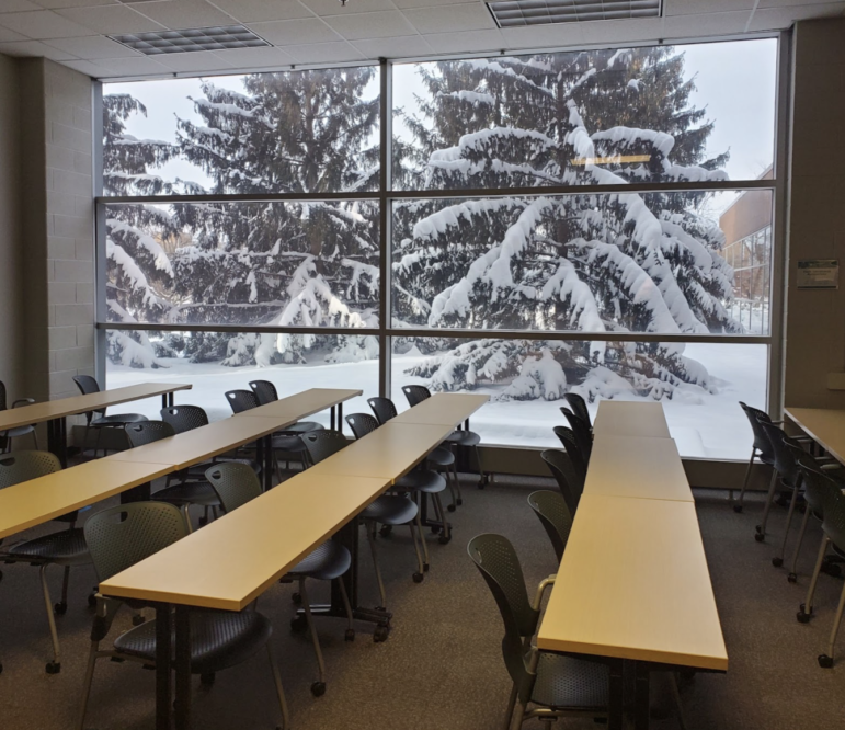 Empty university classroom building with snow-covered trees outside window.
