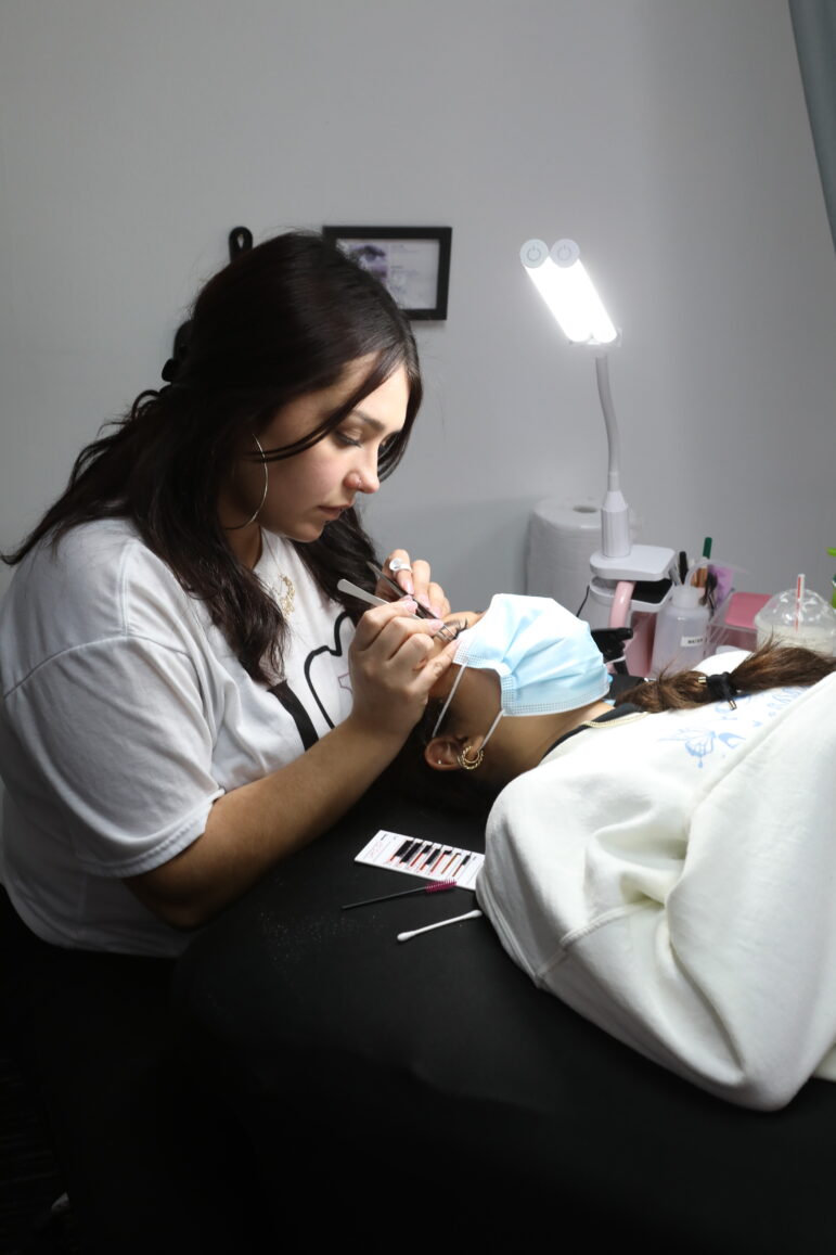 Woman applies eyelash extensions
