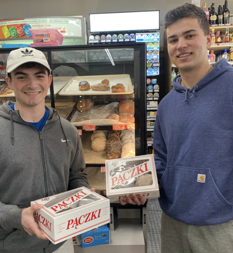 Two college students, each with a box of paczki