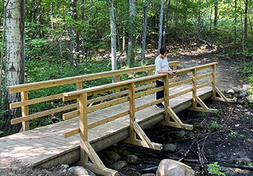 A hiker stops to look at a small stream in Maplehurst Natural Area.