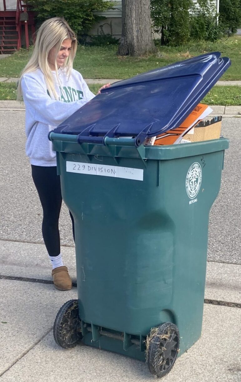 College student checks tall recycling bin.