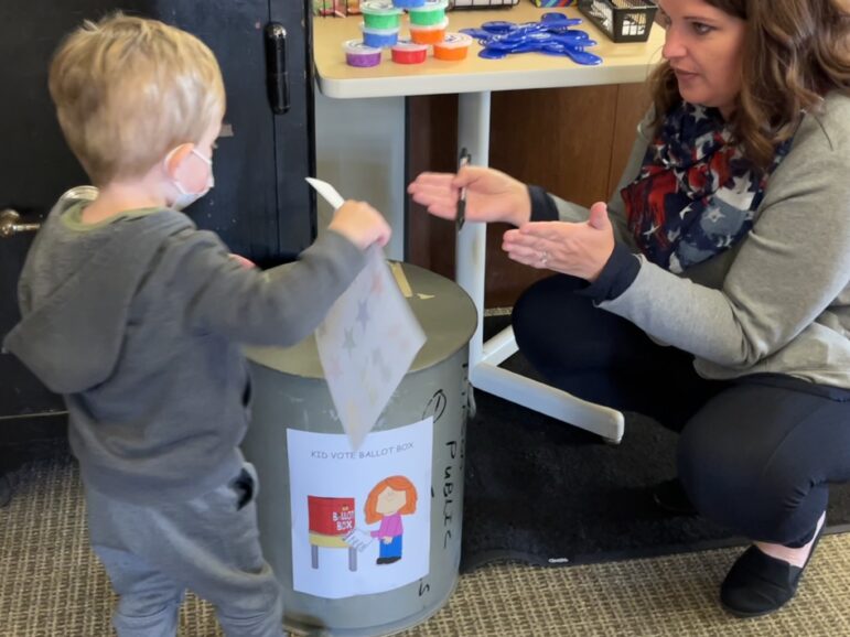 A child is shown how to cast his vote.