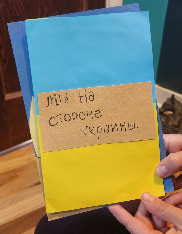 Yuliya Mironova wrote cards for refugees she met in Warsaw and hopes to mail them once they have a more permanent address. The text says “We stand with Ukraine” in Russian.