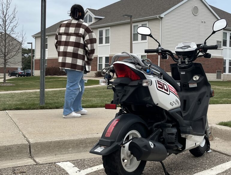 Student walking past moped outside University Village, located in South Neighborhood. This is where the majority of moped thefts are reported.