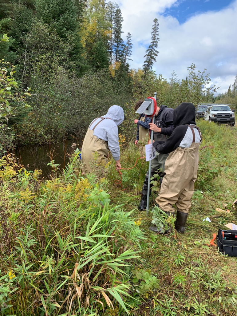 High school students install a monitoring station on the Pine River.