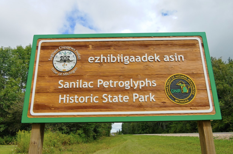 A sign in English and the Anishinabemowin language welcome visitors to Sanilac Petroglyphs State Historic Park.