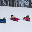 Girls laugh while riding down the tubing hill.