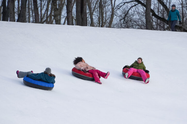 Girls laugh while riding down the tubing hill.