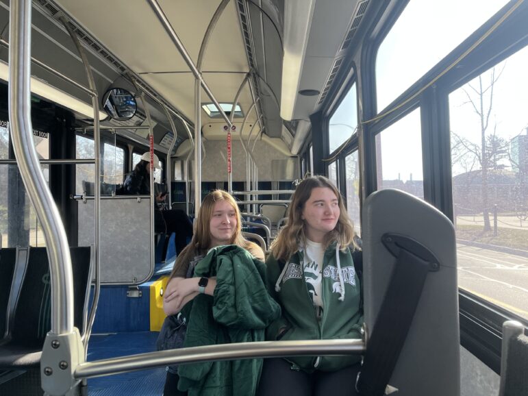 A picture of two Michigan State University Students riding a CATA bus during one of the Listening Bus sessions. 