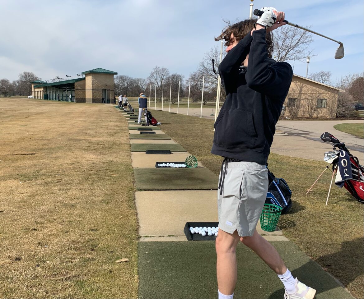 A golfer swings on the driving range at Forest Akers.