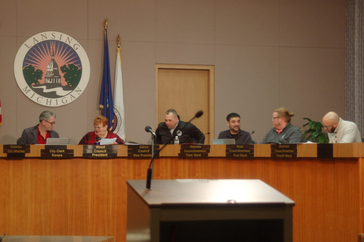 (Left to right) Chris Swope, Carol Wood, Jeremy Garza, Adam Hussain, Ryan Kost and Brian T. Jackson sit for the Lansing City Council Meeting on Jan. 23. Photo by Katie Finkbeiner.