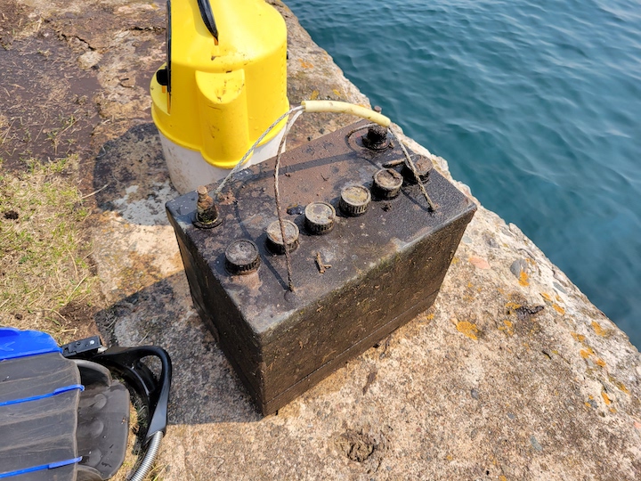 Don Fassbender and Kevin Ailes recover trash that has been underwater for decades. This car battery found in Marquette Harbor dates back to the 1950s.