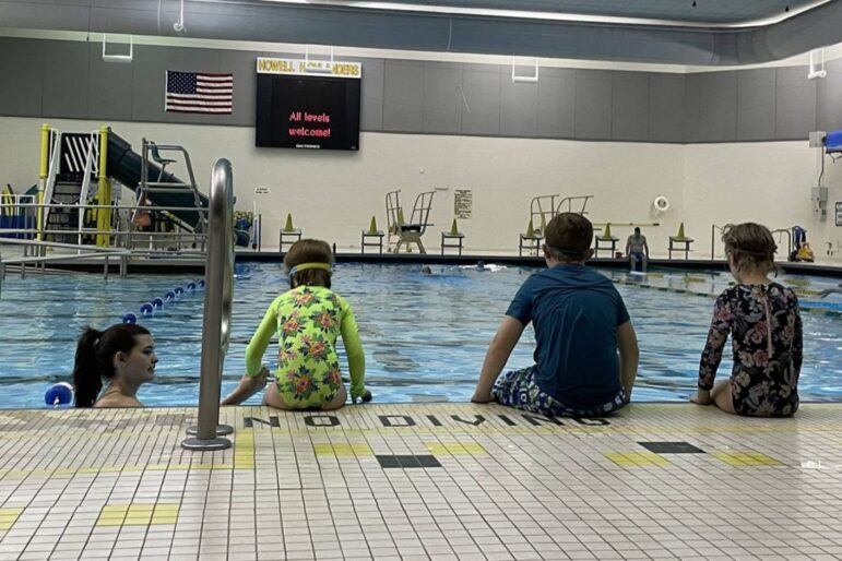 Children take turns falling off the edge of the pool with Mia Dodd’s support, teaching them how to safely enter the pool