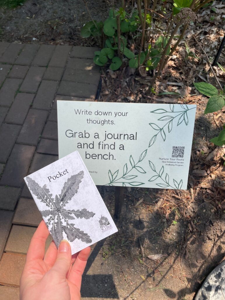One of the Nurture Your Roots locations in the Beal Botanical Garden and the pocket journal where visitors can write down their experiences in the garden guided by the program.