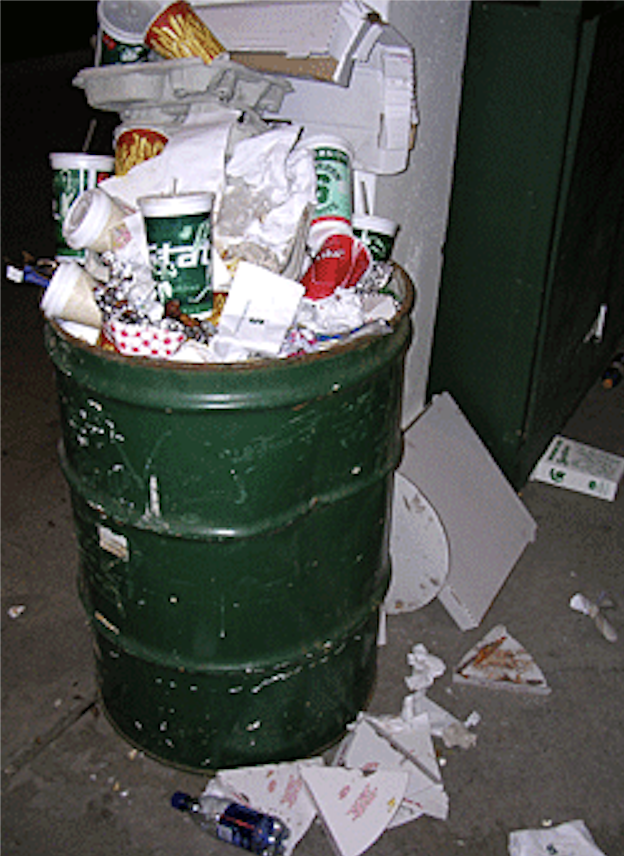 Litter overflowing a trash barrel at a Michigan State University football game.