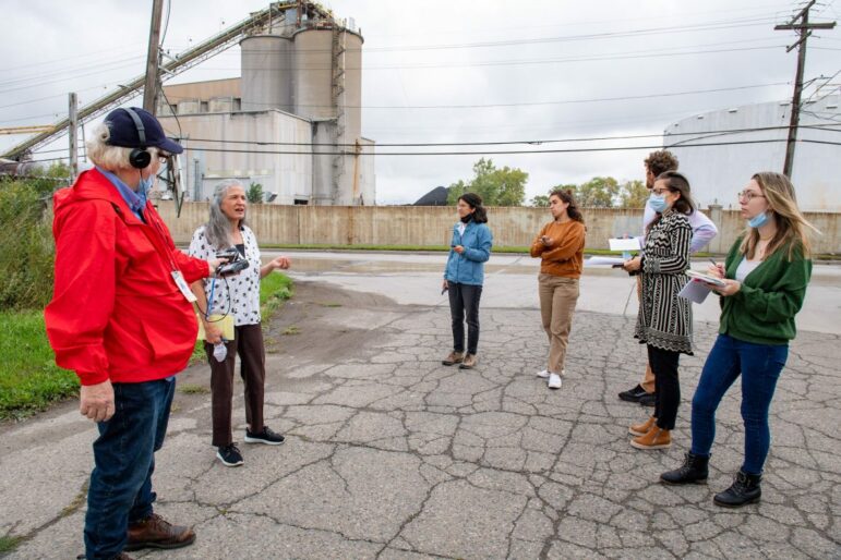 Genevieve Fox, far right, and other journalists tour the Carmeuse Lime Manufacturing Plant in River Rogue, and hear Simone Sagovic, the project manager at the Southwest Detroit Community Benefits Coalition, speak about health problems of people living nearby.