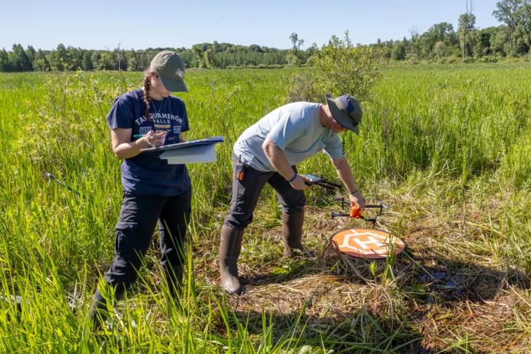 Student researchers Ava Whitlock and Brody Glei get ready to fly a drone equipped with a heat-sensitive camera to find rare eastern massasauga rattlesnakes.