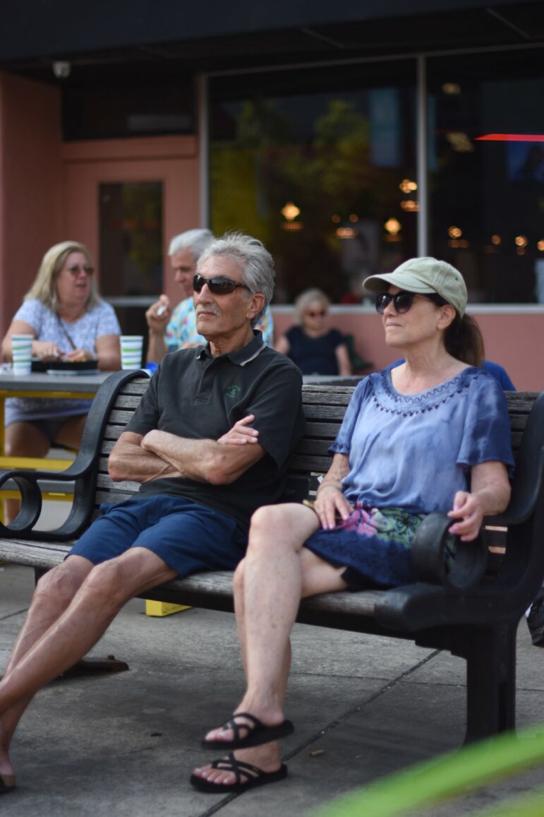 Audience members stop to take in and listen to Caleb Robinson and his band, Reaching, as they perform for East Lansing Summer Concert Series. Photo by Somer Sodeman