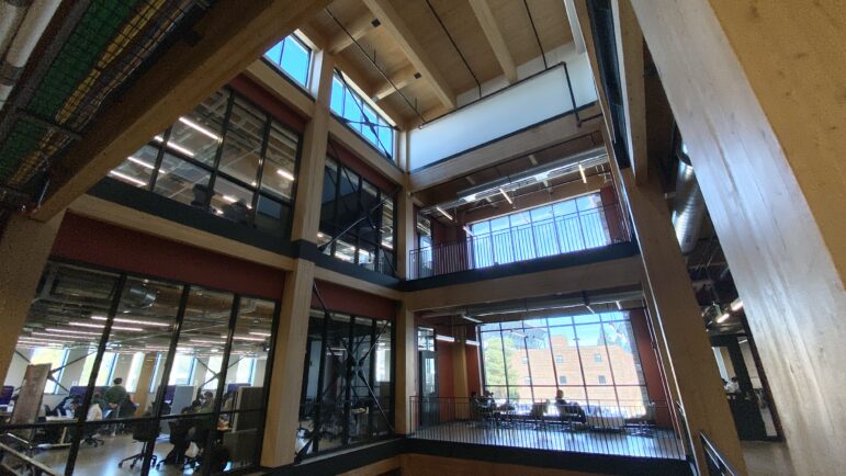 The interior of the MSU STEM Building. Floors 2 and 3 can be seen. Large windows are framed by mass timber beams holding up the structure.